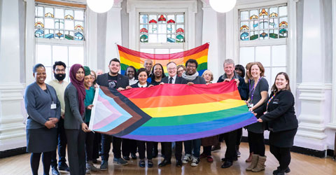 Mayor of Newham with council workers raising the new progress rainbow flat that incorporate the well known rainbow design but additionally now represent trans, black, and ethnic minority communities.