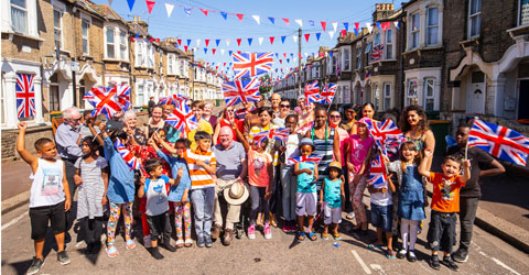 The mayor with residents on the street in celebration. Red, white and blue bunting hung between the terraced houses
